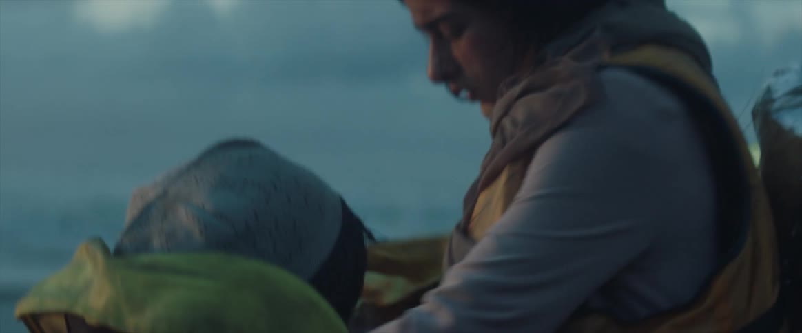 A woman walks over to a child to wrap them in a blanket