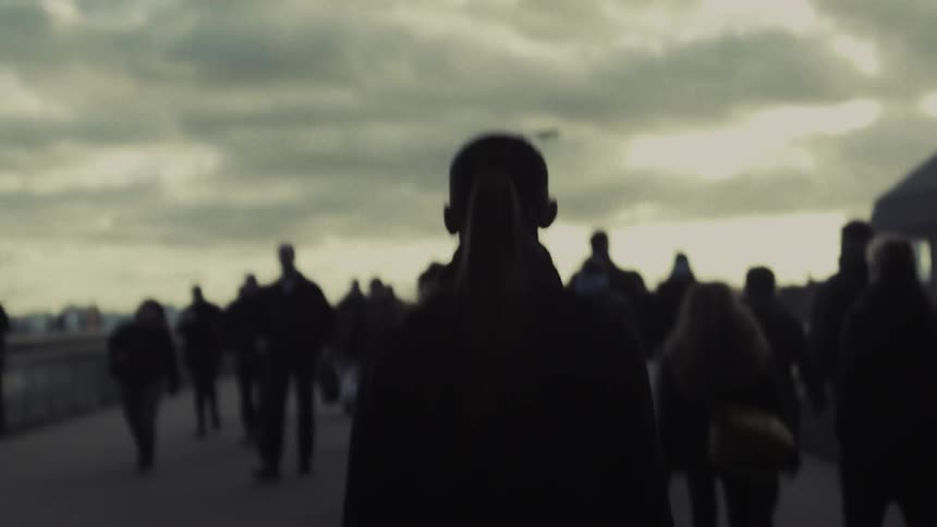 Many people walking on a bridge on a cloudy day
