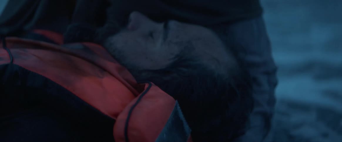 A woman holds an unconscious man in her lap