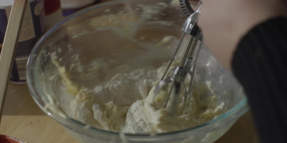 Two people mix dough in the kitchen