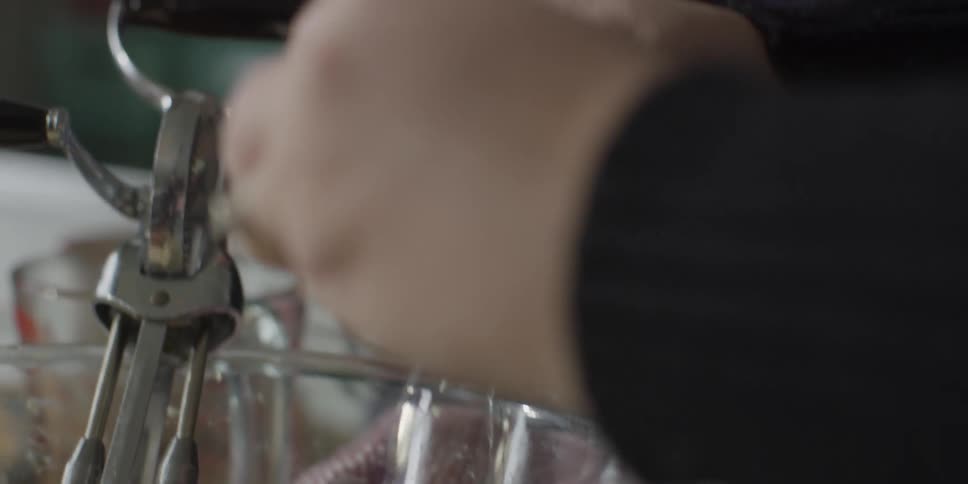 Hands crack an egg into a mixing bowl