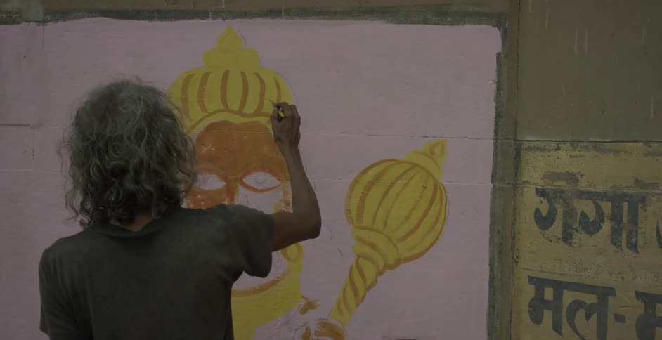 A thin woman paints on a wall