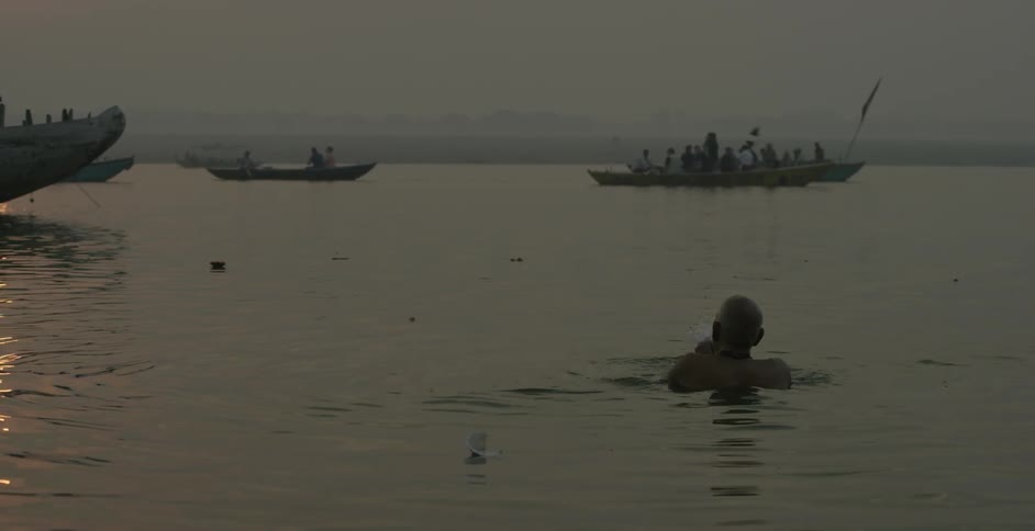A man floats in the water as boats sail nearby
