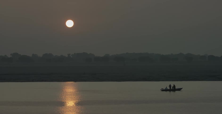 People stand on a boat being rowed at sunset