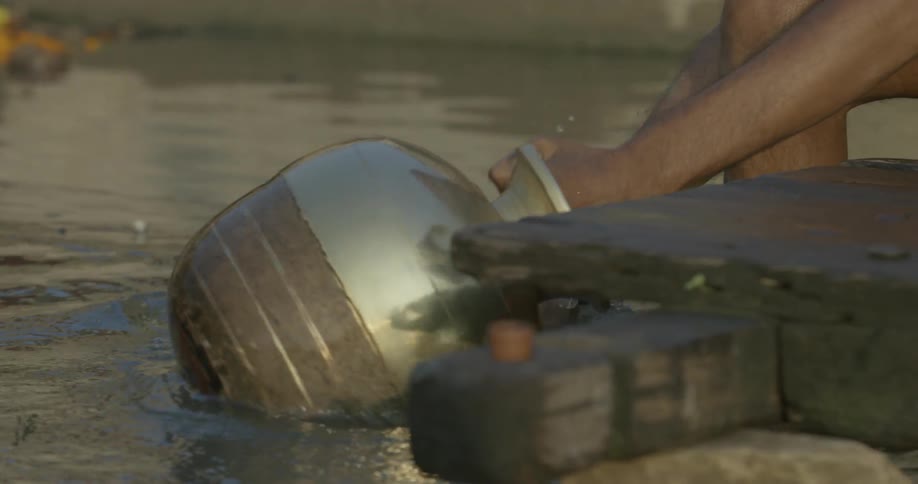 Person spins a vase in a body of water washing it off