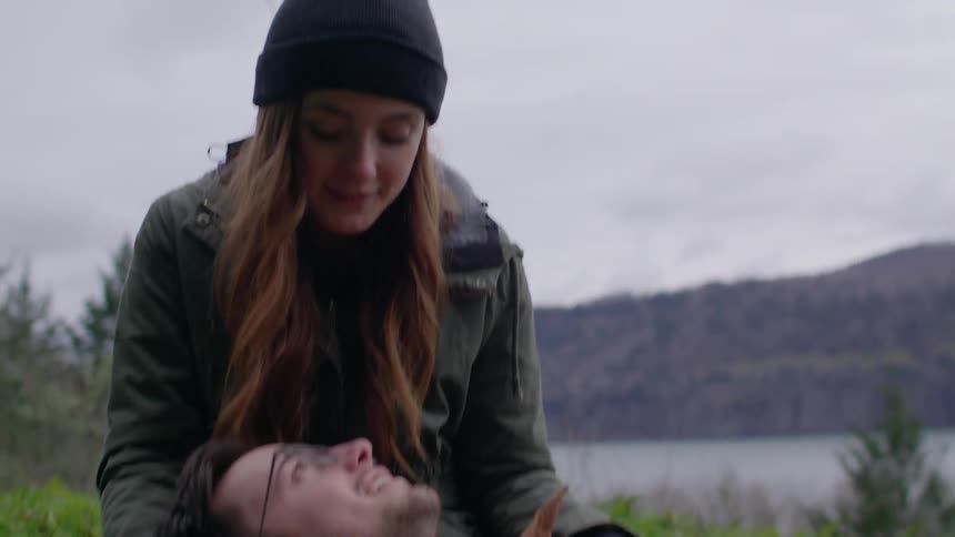 A man is lying in a woman's lap on a cloudy day