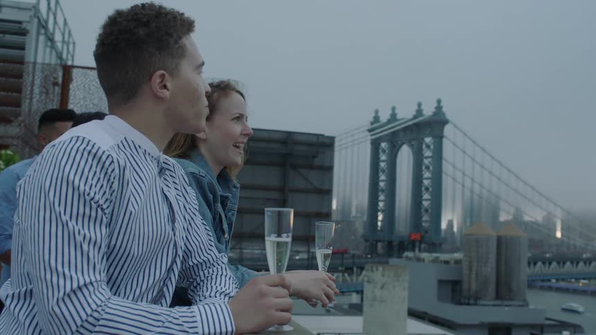 A man and woman have a drink while looking over the city