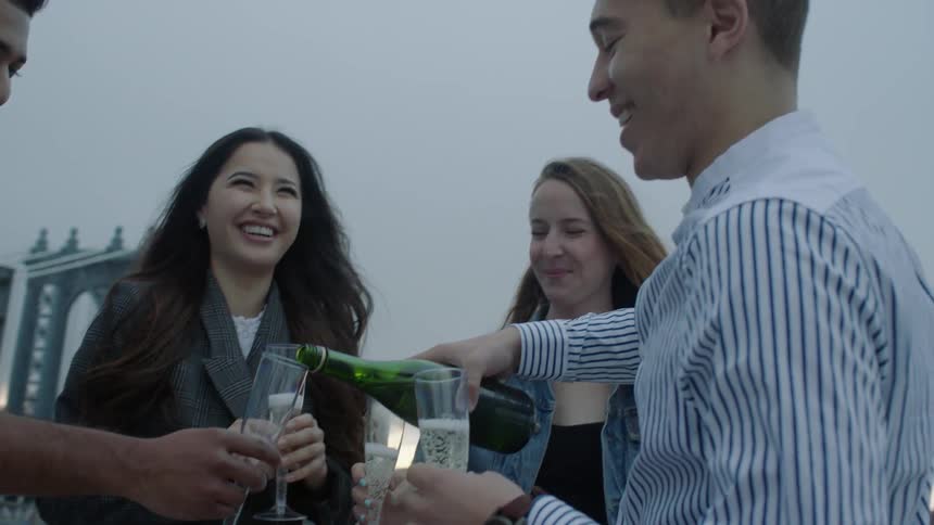 Men and women standing outside pouring champagne into glasses
