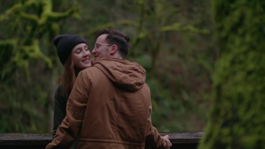 A man and woman kiss in the forest