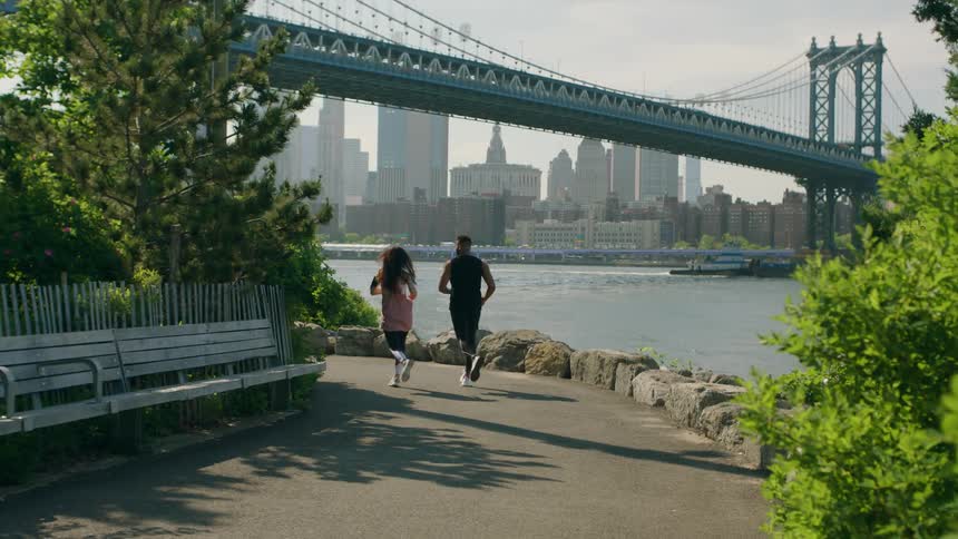 A man and woman jog by the water