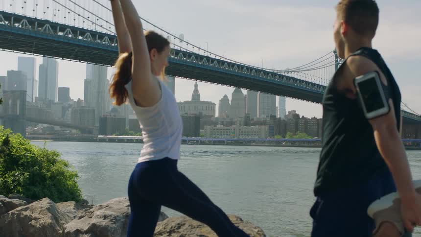 A man and woman stretch in a city park