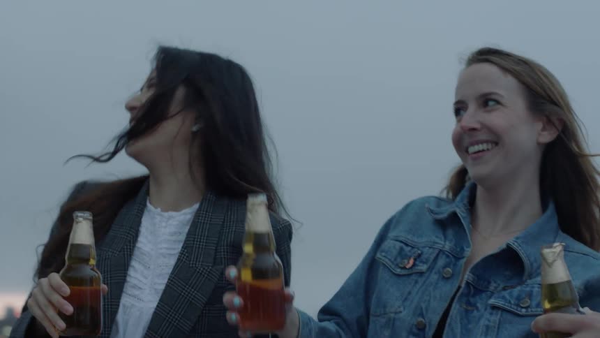 Man opens a bottle of beer and toasts with his friends
