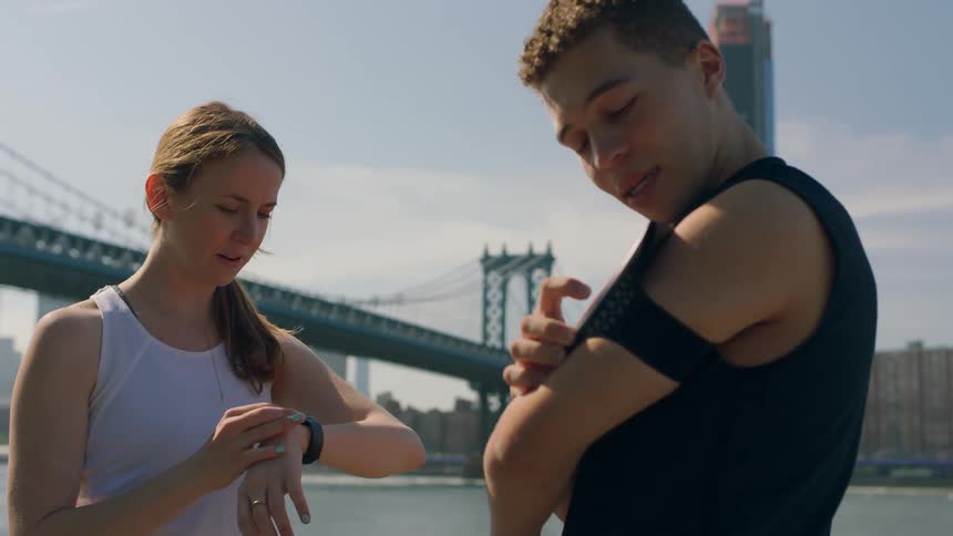 A man and woman check their devices on a windy day