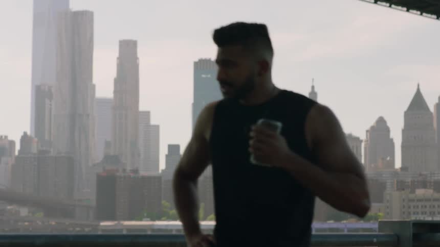 A man is stretching by the water near the city