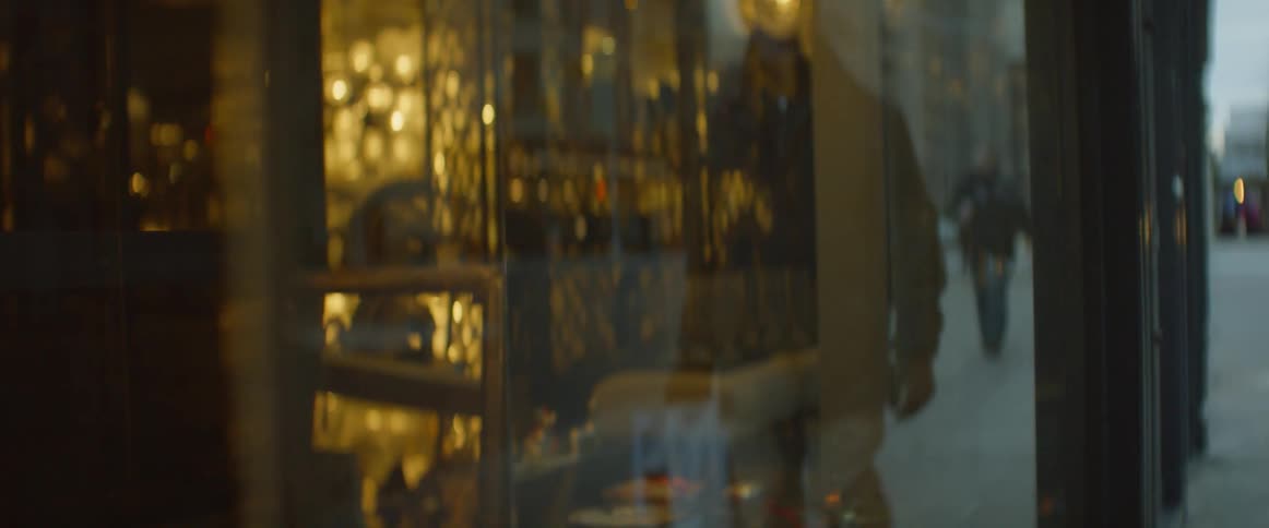 Pedestrians are reflected in the glass windows of a city shop