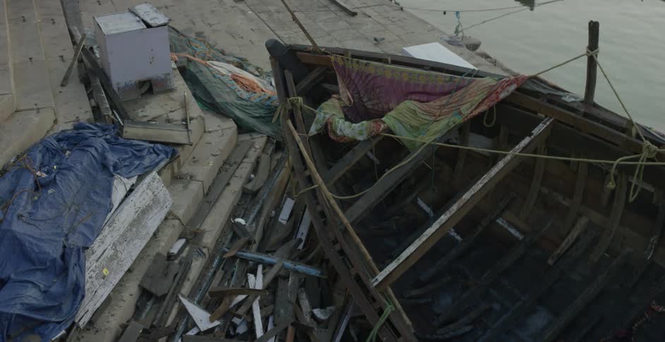 A boat sits on a wooden dock near a pile of wood