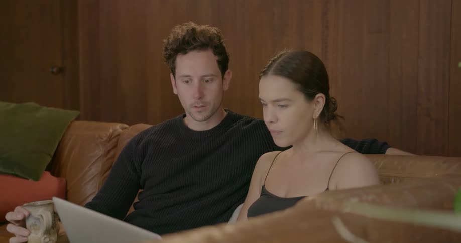 A couple talk in front of a laptop