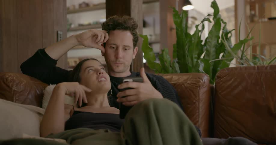 A man and woman cuddle and talk on a couch