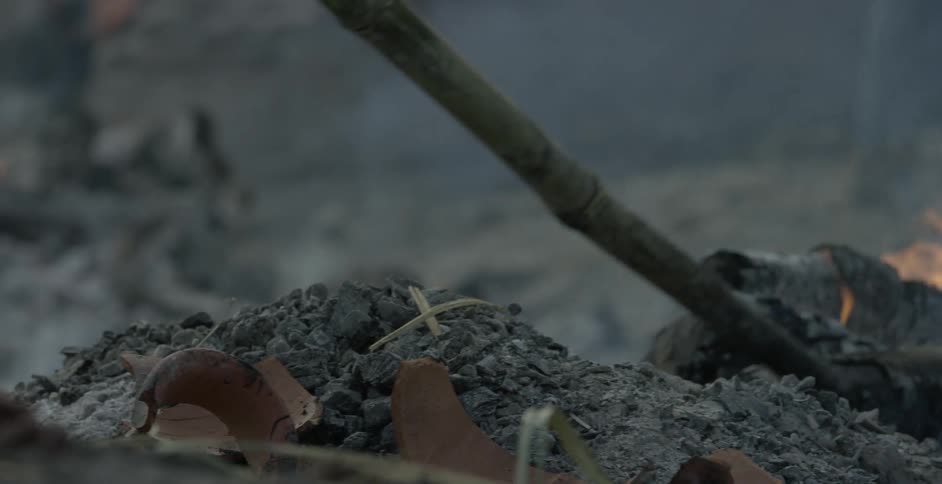 A person sirs some ash with a stick
