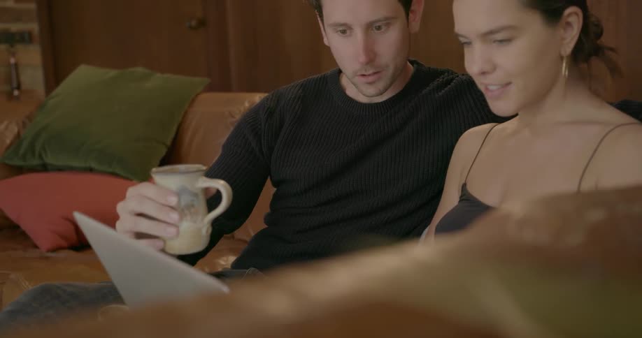 Man and woman sitting on a couch looking at a laptop