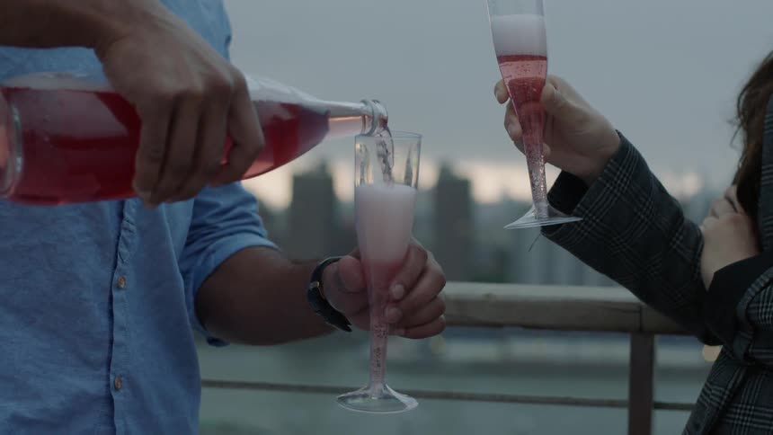 A man is pouring champagne and toasting with a woman