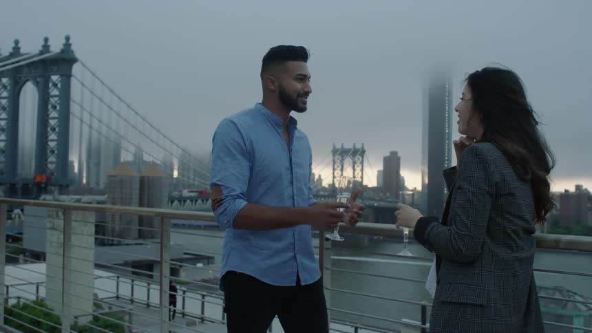 A man and woman drink by a railing