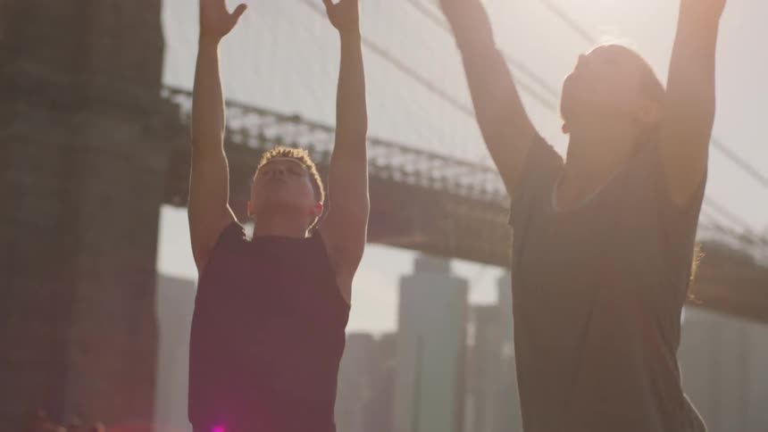 A man and woman do yoga in a city park