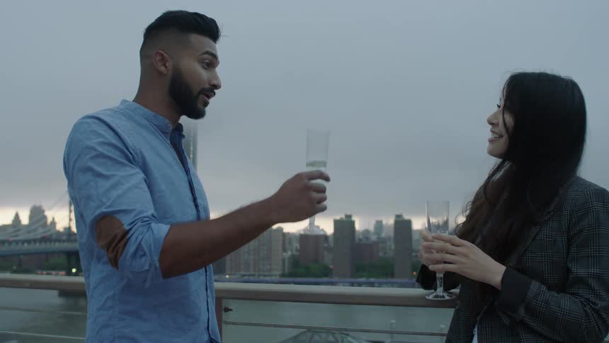 A man and woman drink champagne in a city