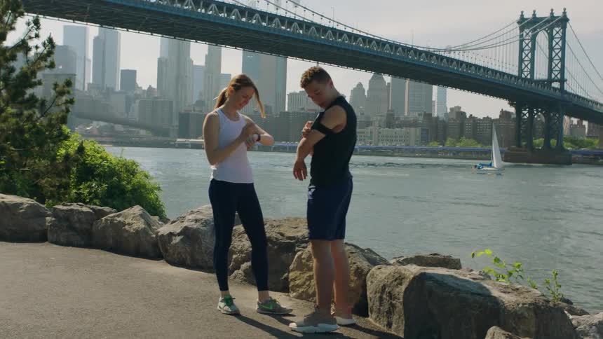 A man and woman jogger check their fitness trackers