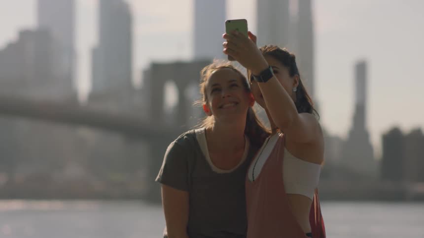 Two girls take selfies near a body of water