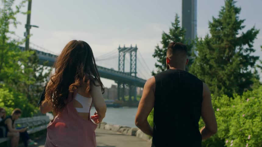 A man and woman run together down a rail
