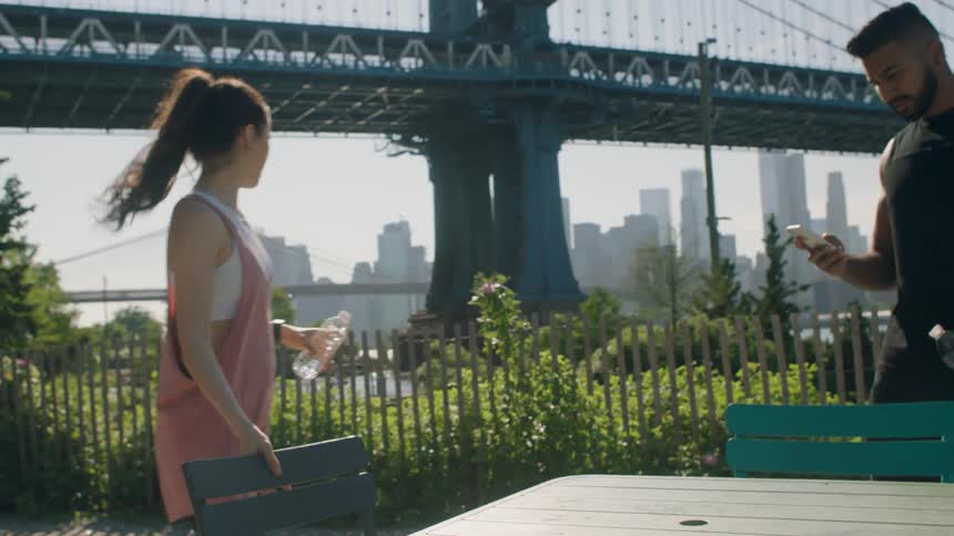 A man and woman jog and stop at a table