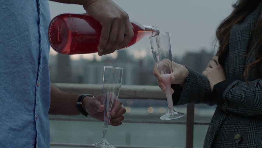 Man pours champagne into a glass for a lady
