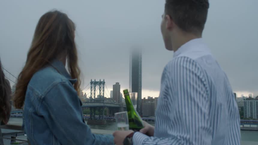 Two couples talk as they drink champagne on a bridge