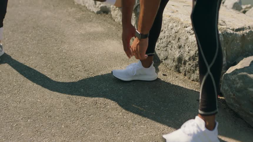 Man and woman stretch standing on a sidewalk next to a river