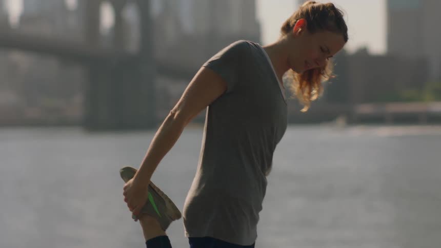 A woman uses her phone by the water near a city