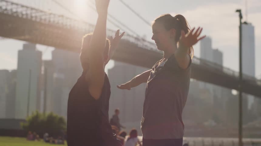 A woman is showing a man how to do a yoga pose
