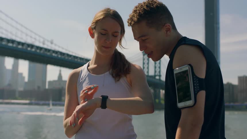 Man and woman look at the woman's watch near the river