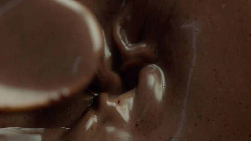 Someone stirs brown liquid