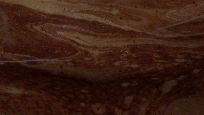 The dark liquid has brown and white swirls moving around
