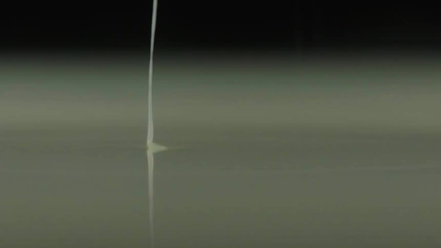 White liquid pours into a pool of liquid