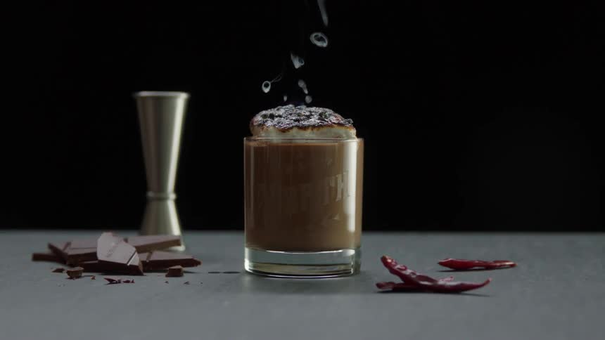 A burning beverage releases smoke and flame into the air