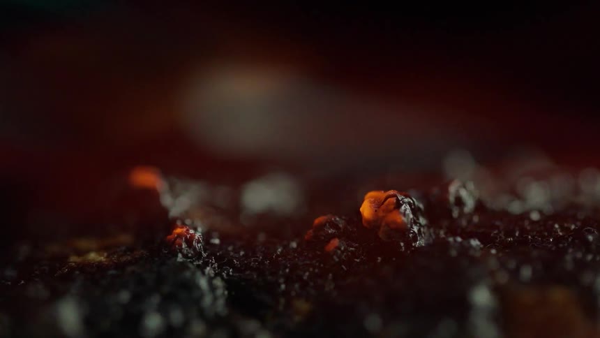 Black liquid bubbles as smoke blows around it