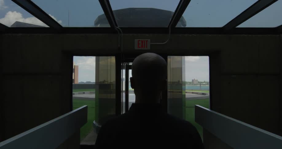 A woman is walking toward the exit of a modern building