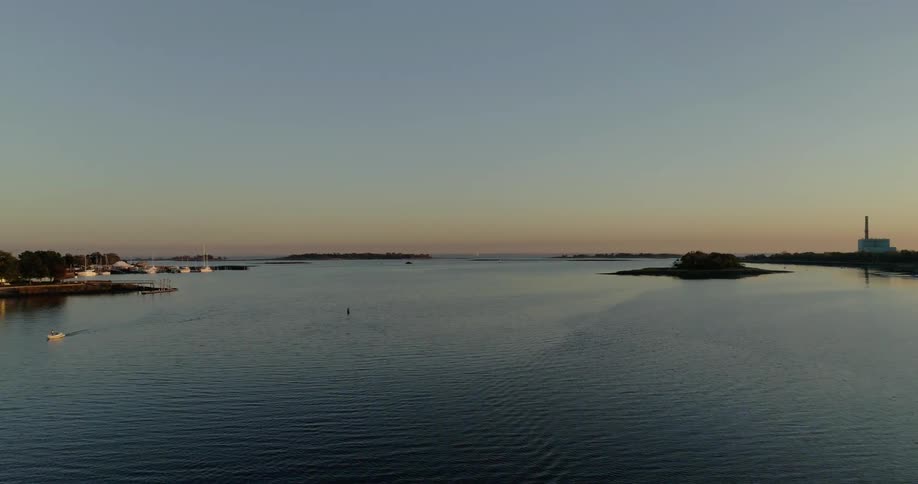 The water is calm near the shore at sunset