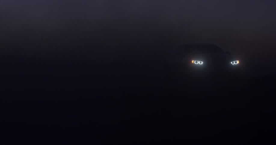 A sports car drives through the haze at night
