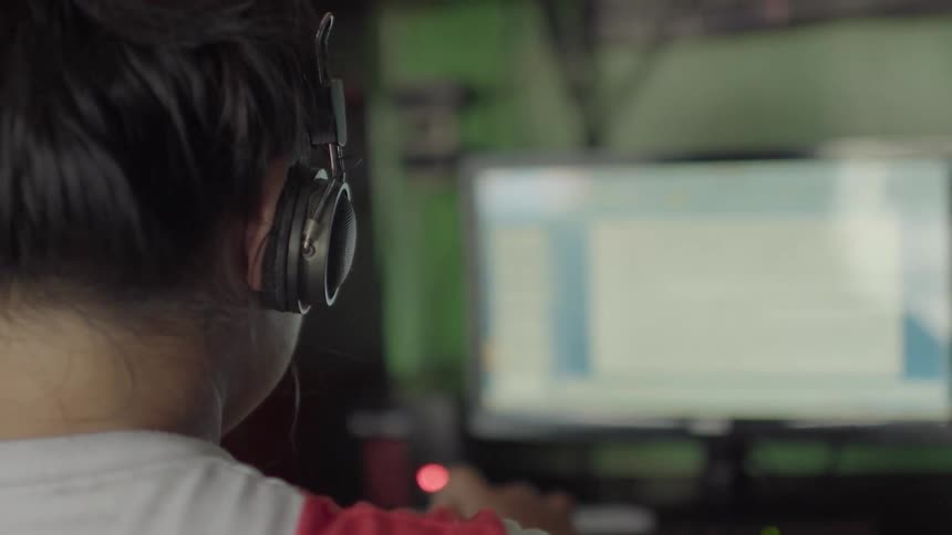 A girl wears headphones at the computer