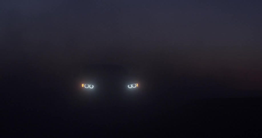 Vehicles lights shine through fog and mist at night