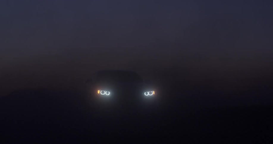 A car drives through a foggy area at dusk