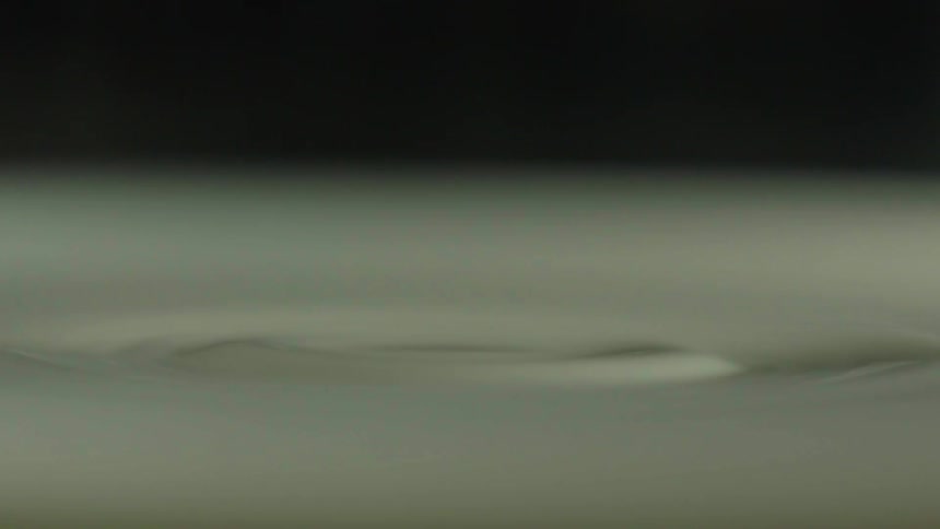 Liquid droplets fall into the liquid below